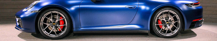 Blue sports car with black rims and red accents on a gray background