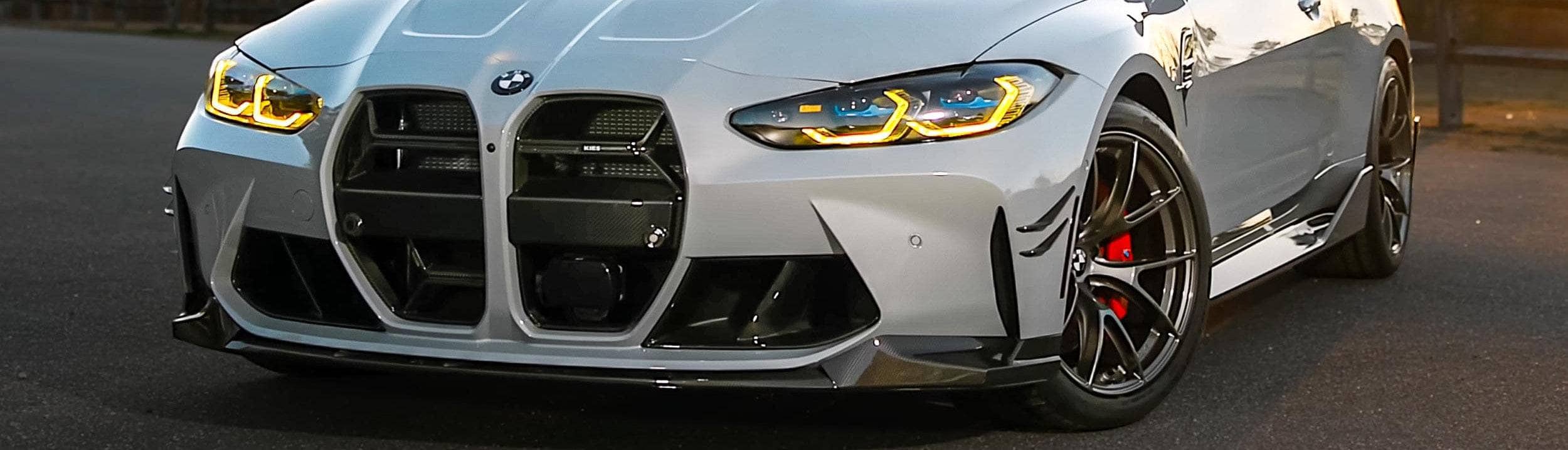 Close-up of a BMW G82 car's front grille and headlights on a road.
